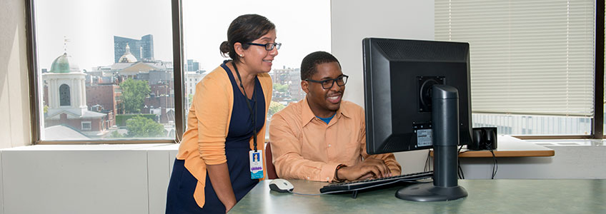 Two people look at a computer