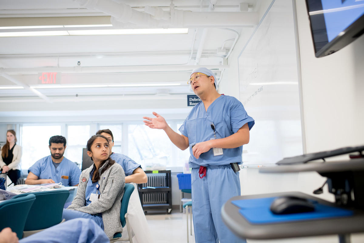 Physician in scrubs gives a presentation to colleagues