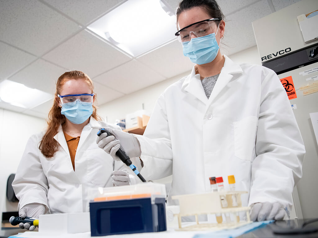 Two researchers at the bench with pipettes