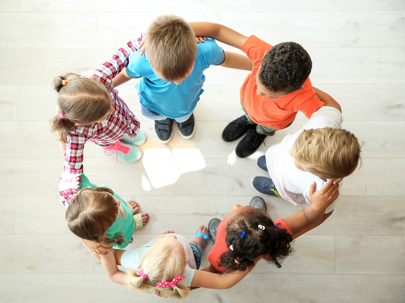 Seven kids of different backgrounds huddle together